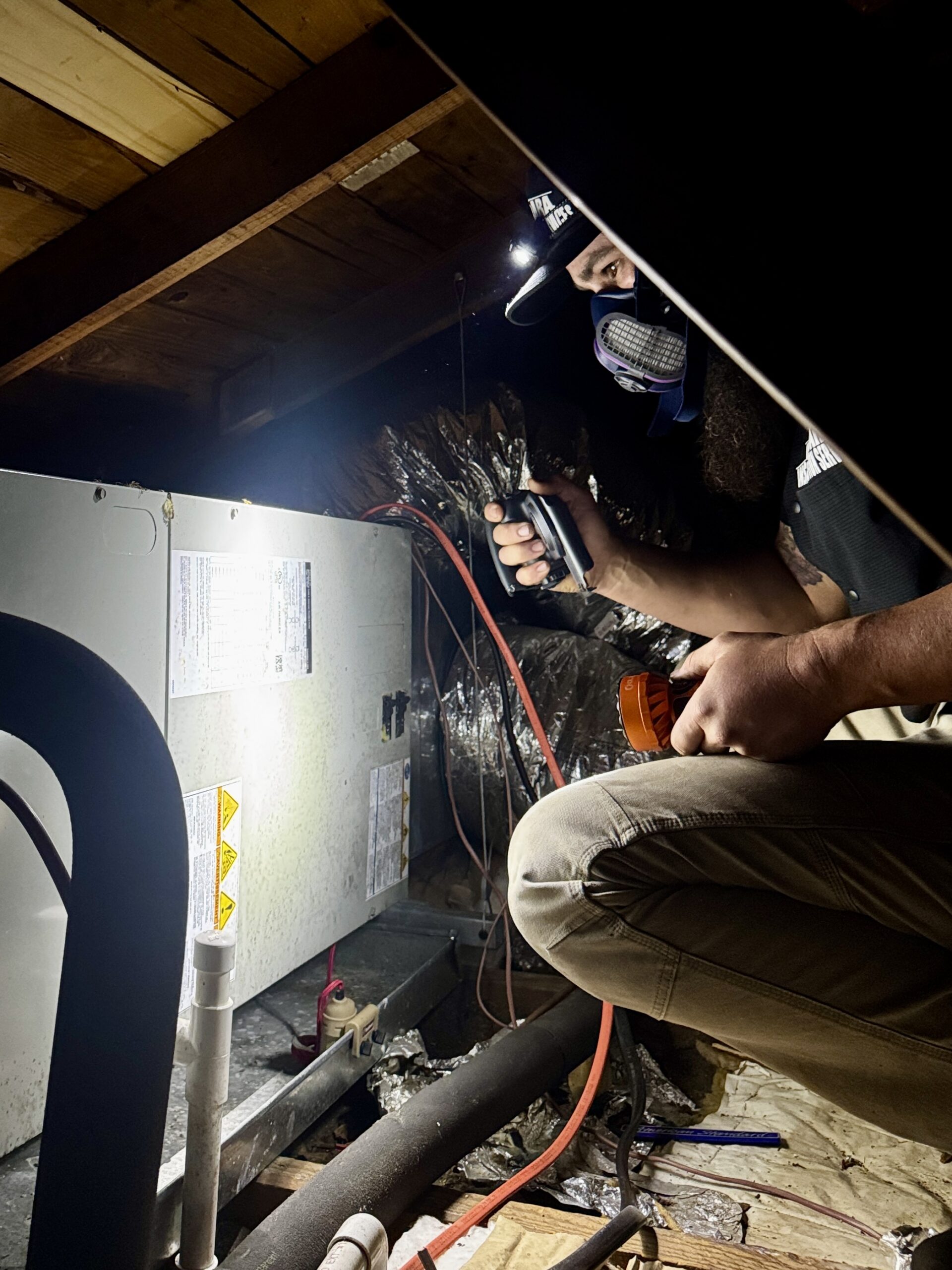 Home inspector in attic taking a photo of an HVAC data label on a furnace unit.